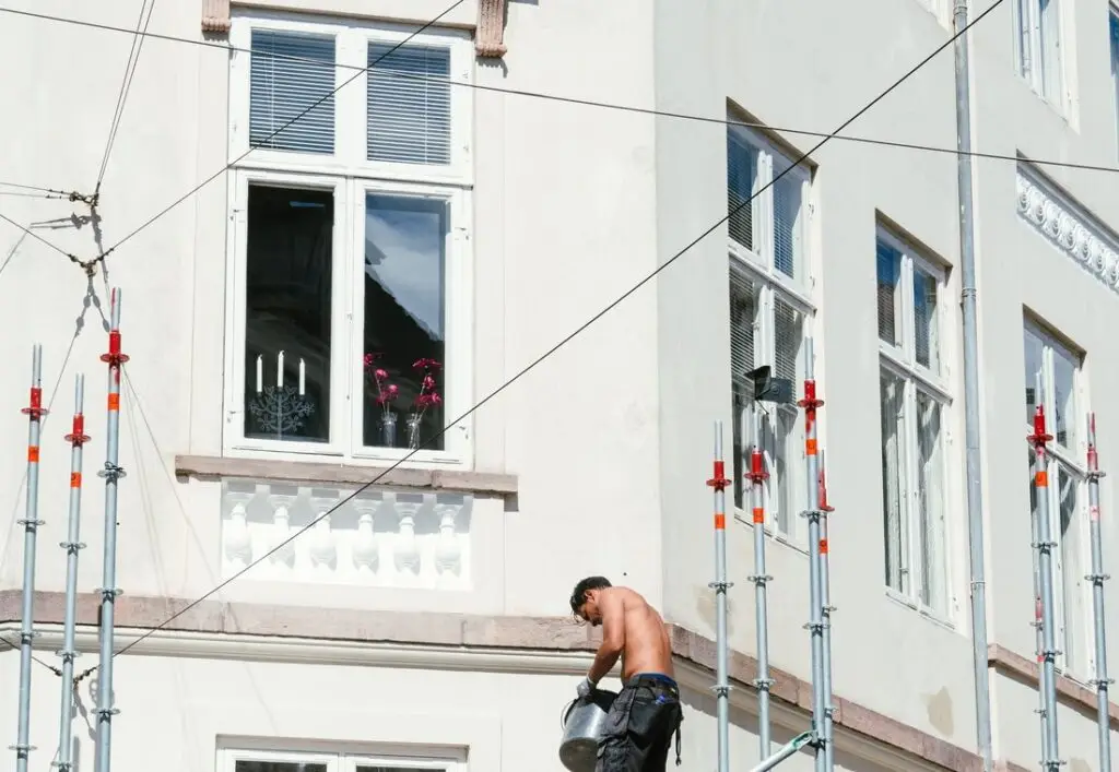 Schilder werkt vanaf een steiger aan de bovenverdieping van een woning