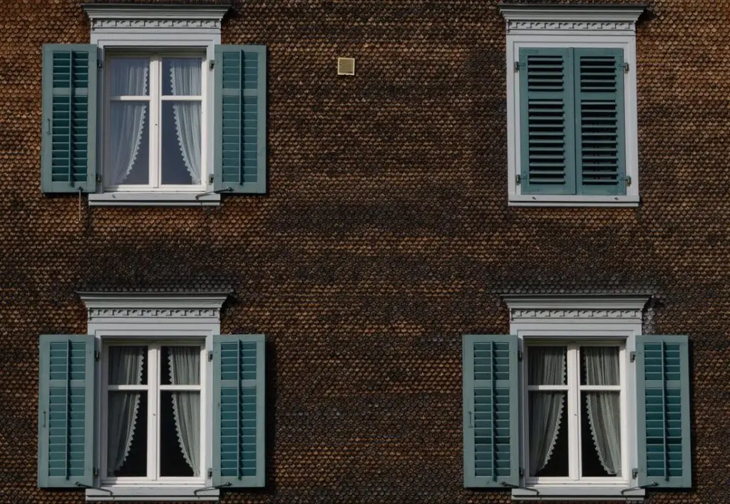 Bakstenen gevel met witte kozijnen en luiken