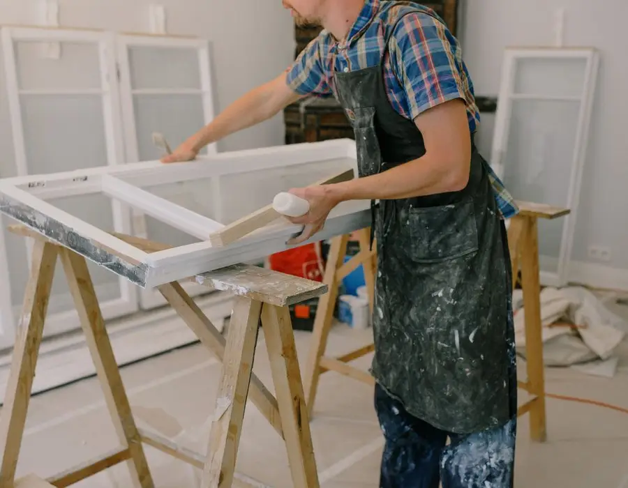 Vakman werkt aan een houten raamkozijn op schragen