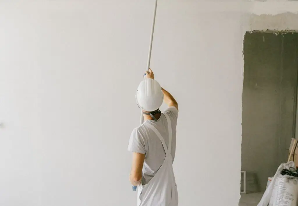 Schilder werkt met een verlengde roller aan een plafond