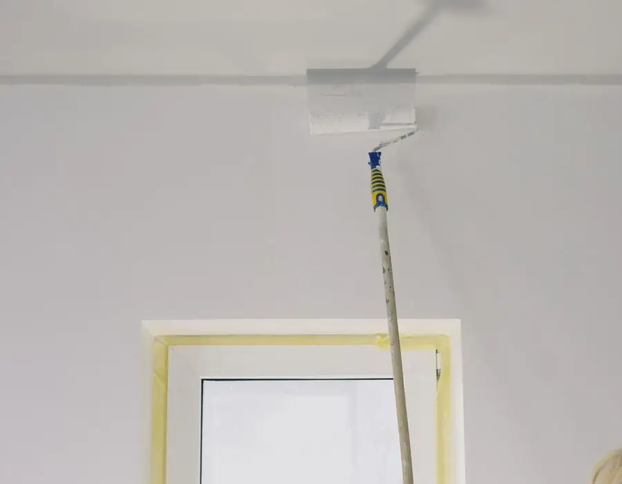 Verfroller op een wit plafond naast een kozijn