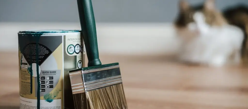 Blik professionele verf met een brede kwast op een houten vloer