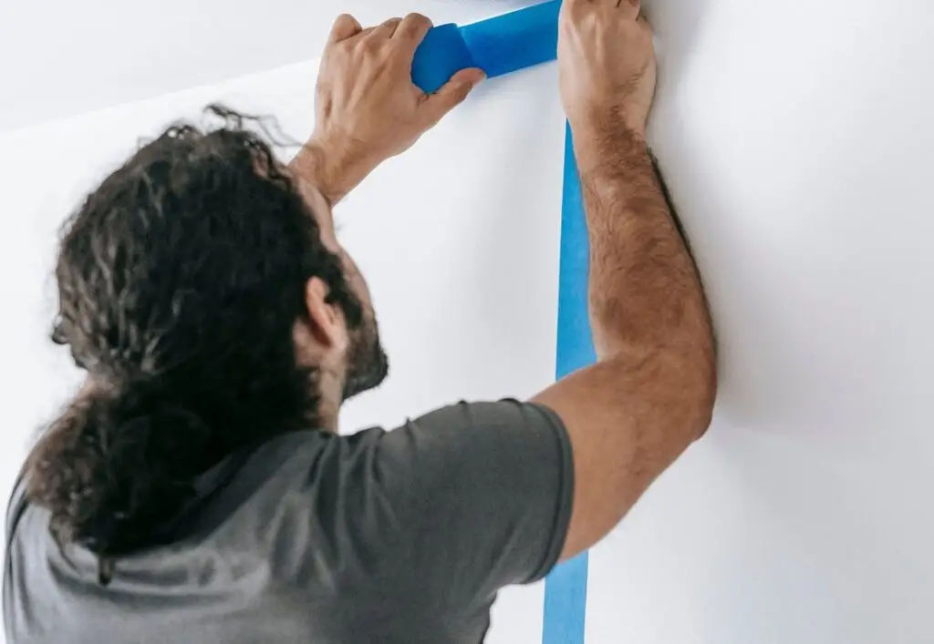 Schilder plakt een muur af met tape voordat het schilderen begint